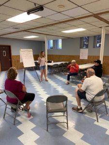 Jessica Rein presents to Ellsworth community members, who listen intently to her in a circle.