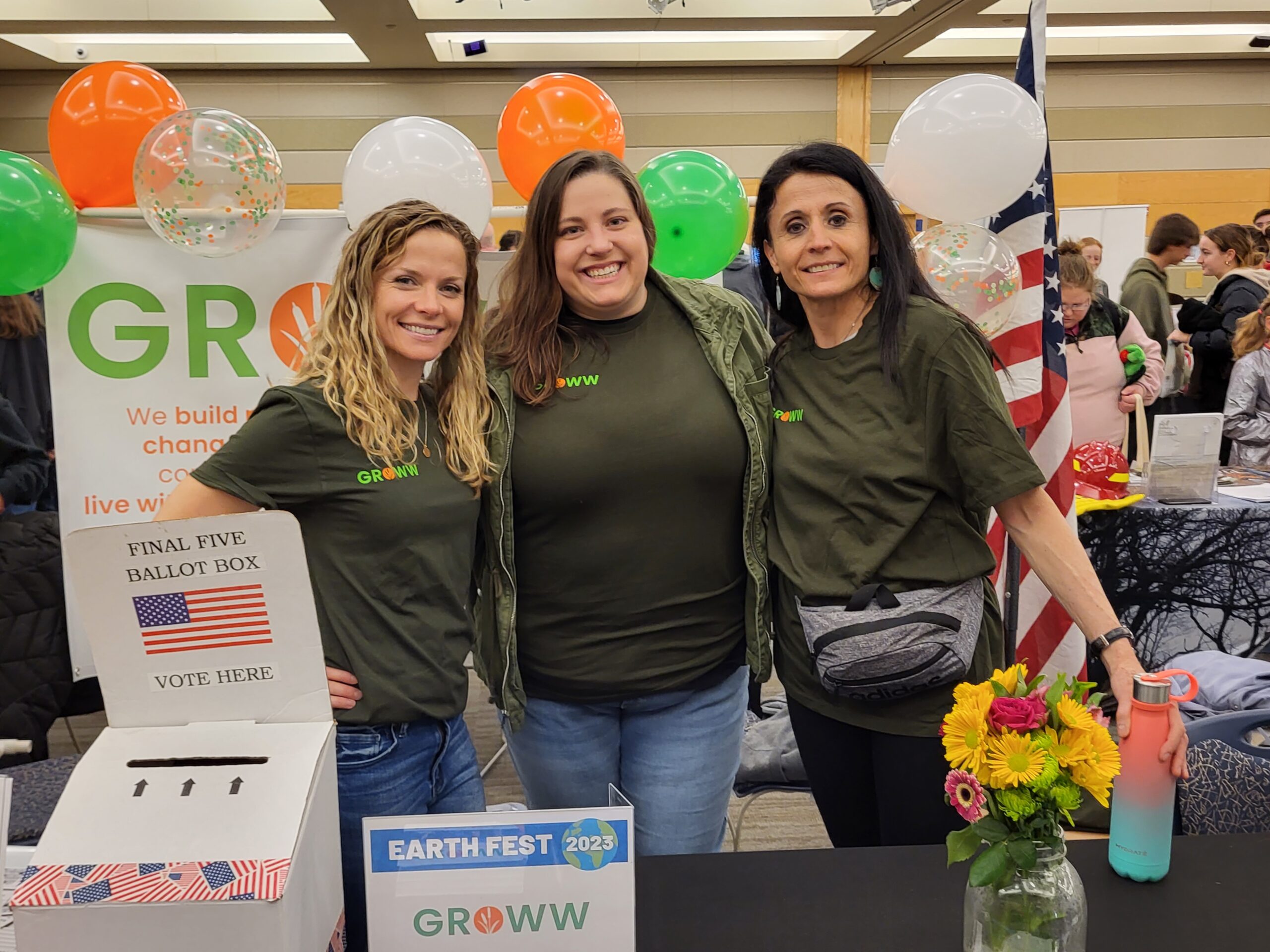 Three GROWW members stand together smiling at the GROWW Earth Fest Booth.